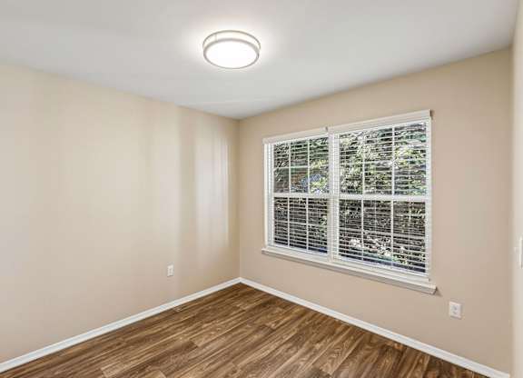 A room with a window and wooden flooring.