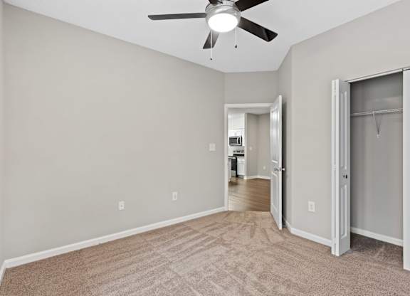 A room with a ceiling fan and a door leading to another room.