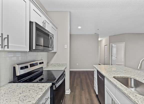 A kitchen with granite countertops and white cabinets.