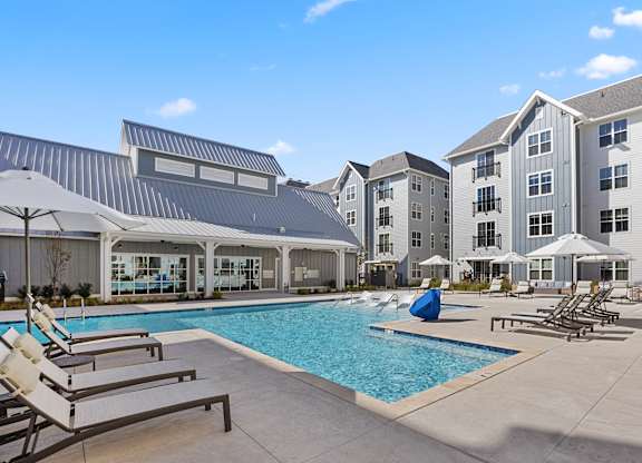 a swimming pool with lounge chairs and umbrellas in front of an apartment building at Blake Farm, North Carolina