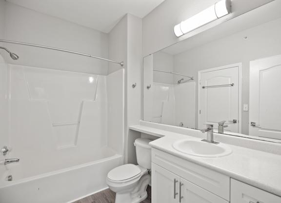 A white bathroom with a toilet, sink, and bathtub.