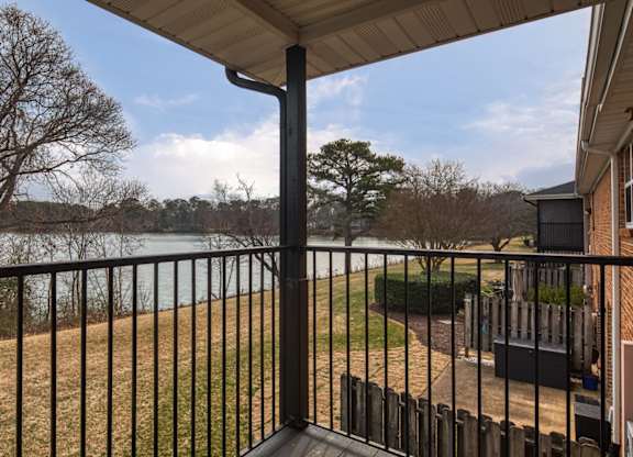 A balcony with a black railing overlooks a body of water.