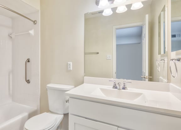 A white bathroom with a toilet, sink, and shower.
