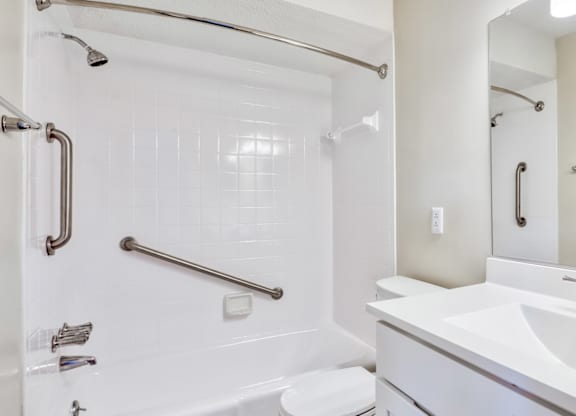 A white bathroom with a sink, mirror, and shower.