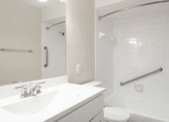 A white bathroom with a toilet, sink, and shower.