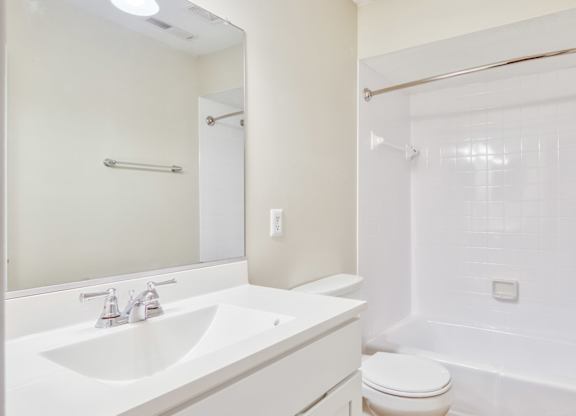 A white bathroom with a sink, toilet, and bathtub.