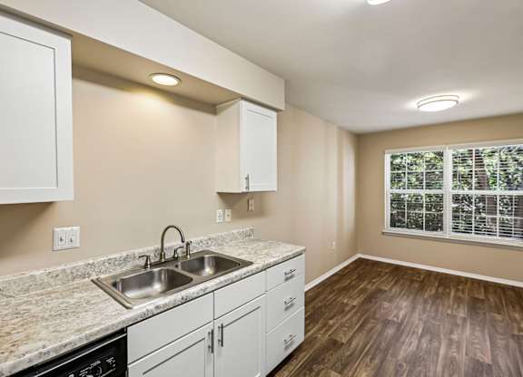 A kitchen with a sink, cabinets, and a window.