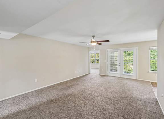 A room with a ceiling fan and carpeted floor.