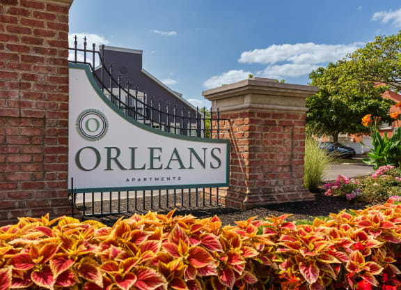 the sign for orleans apartments in front of a gate and flowers at Orleans Apartments, Columbus, 43221