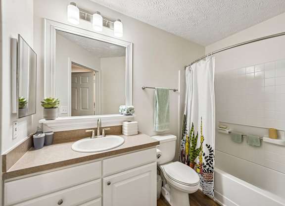 A white bathroom with a sink, toilet, and shower.