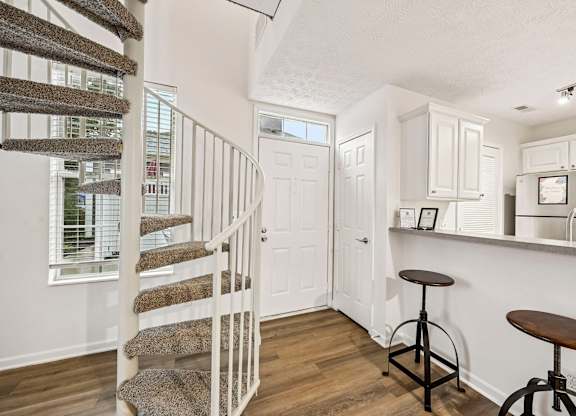 A white interior with a staircase and bar stools.