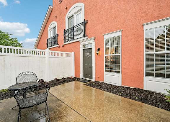 A patio with a chair and a table is in front of a house.