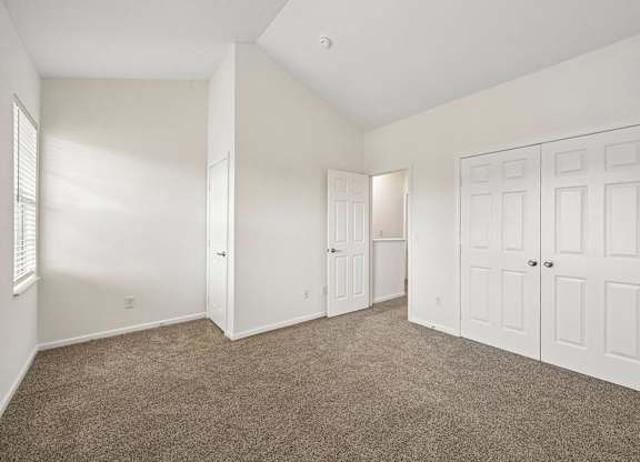 A room with white walls and carpeted floor with a door on the right.