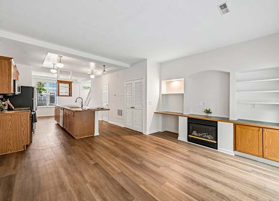 A modern kitchen with wooden floors and a fireplace.