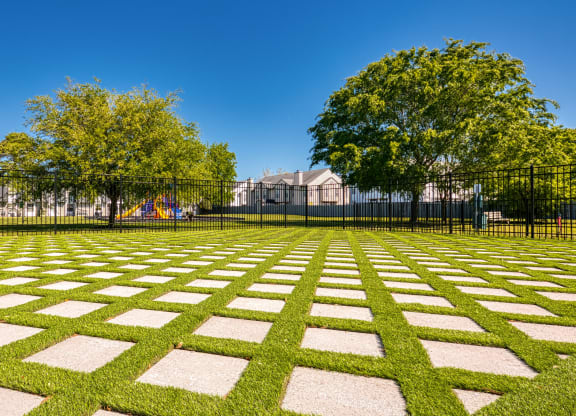 a grassy area with trees in the background and a black fence in the foreground