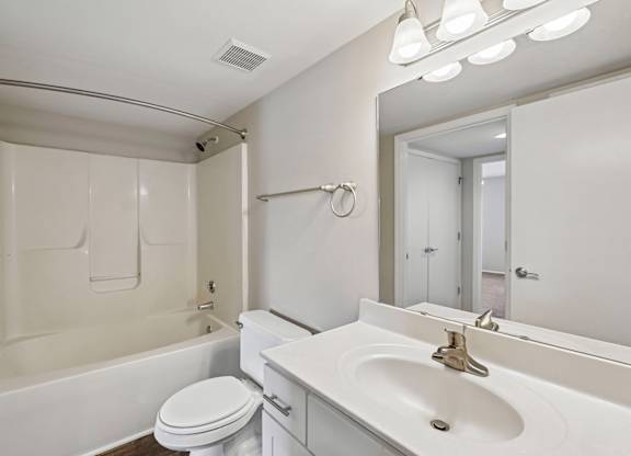 A white bathroom with a toilet, sink, and mirror.
