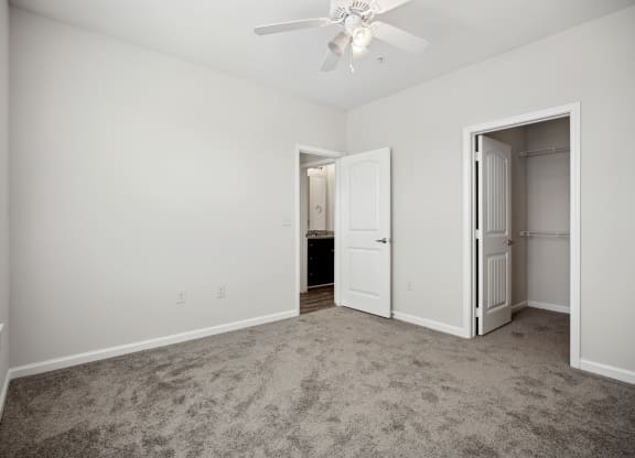 an empty living room with carpet and a ceiling fan