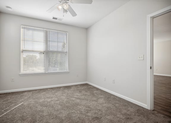 an empty room with a window and a ceiling fan