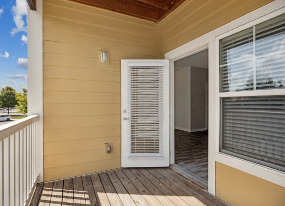 the deck of a home with a white door and a balcony