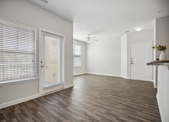 an empty living room and dining room with white walls and wood flooring