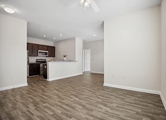 an empty living room and kitchen with white walls and wood flooring
