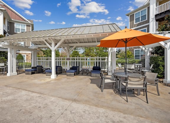 a patio with an umbrella and tables and chairs