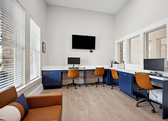 a room with a desk and chairs and a tv on the wall