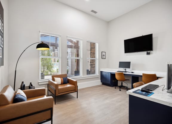 a living room with couches and chairs and a desk with a computer and monitor