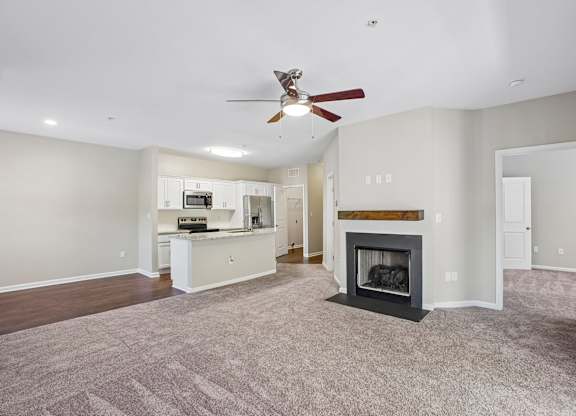 A spacious living room with a fireplace and a ceiling fan.