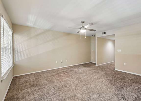 A room with a ceiling fan and carpeted floor.