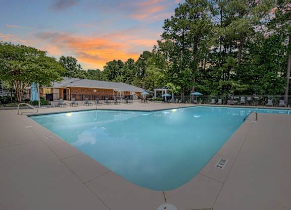 A large swimming pool surrounded by trees and a building in the background.