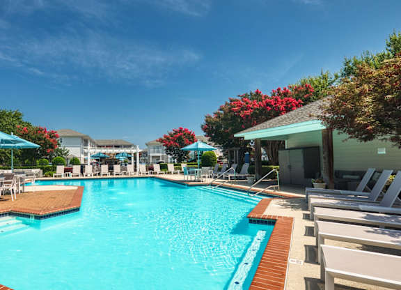 A large swimming pool surrounded by lounge chairs and umbrellas.