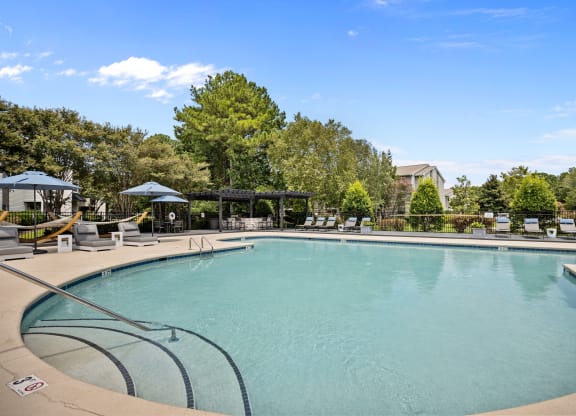 a swimming pool with trees in the background and a blue sky