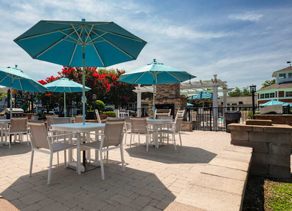 A patio with tables and chairs under umbrellas.