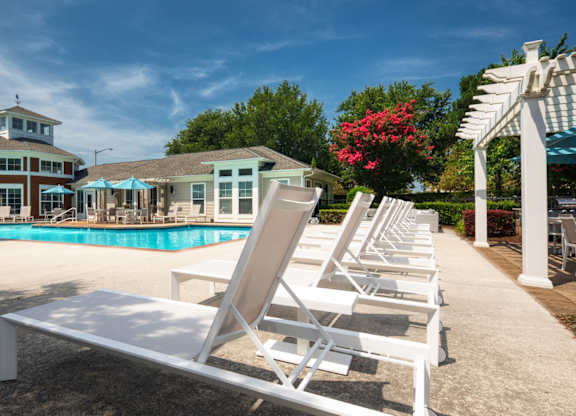 A poolside area with sun loungers and a building in the background.