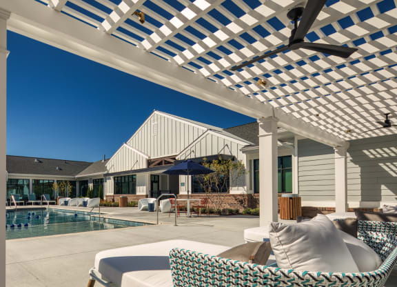 a patio with a pool and chairs under a pergola