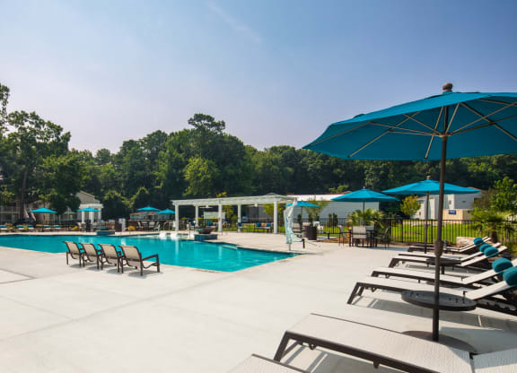 a swimming pool with lounge chairs and umbrellas