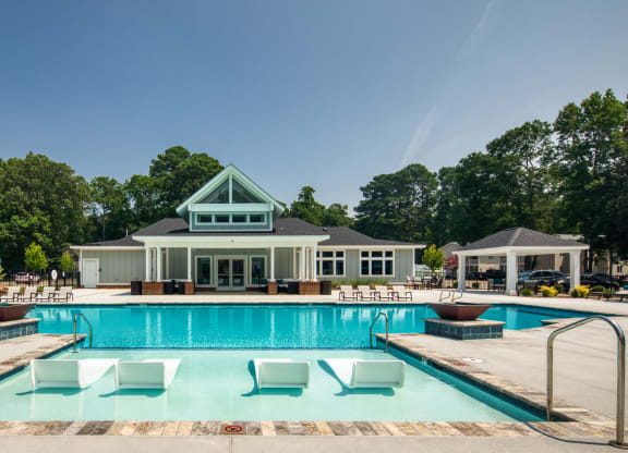a swimming pool with lounge chairs and a club house in the background