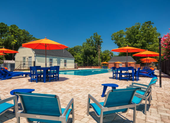 a pool and patio with blue chairs and umbrellas