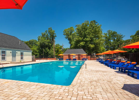 our resort style swimming pool is surrounded by lounge chairs and umbrellas