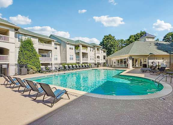 A large swimming pool surrounded by lounge chairs and a gazebo-like structure.