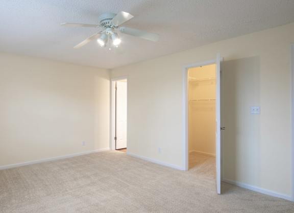 A room with a ceiling fan and carpeted floor.