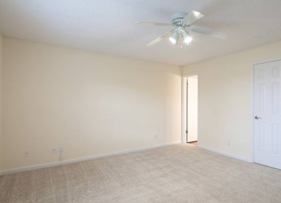 A room with a ceiling fan and carpeted floor.