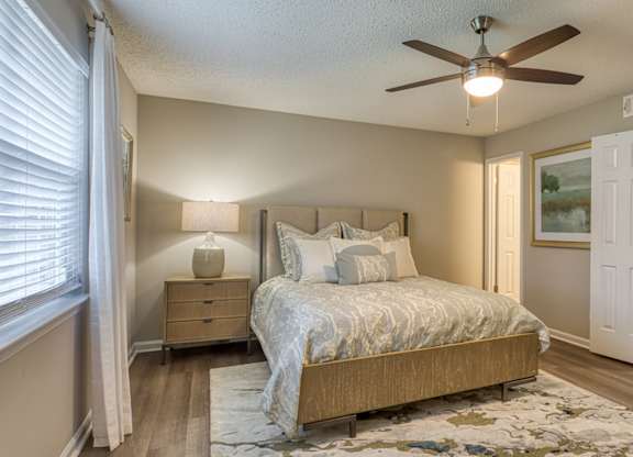 A bedroom with a bed, nightstand, and a ceiling fan.