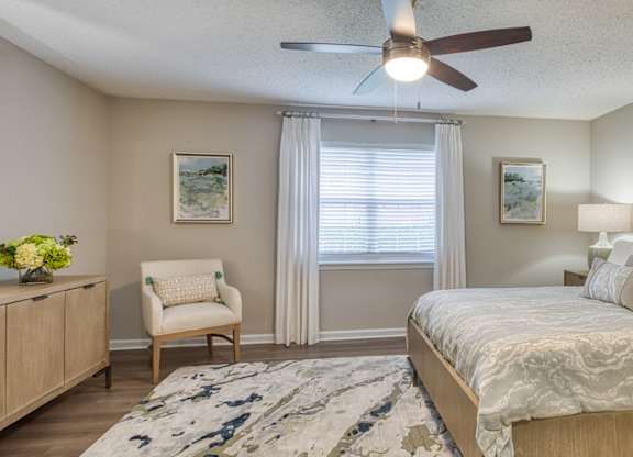 A bedroom with a bed, chair, and a ceiling fan.