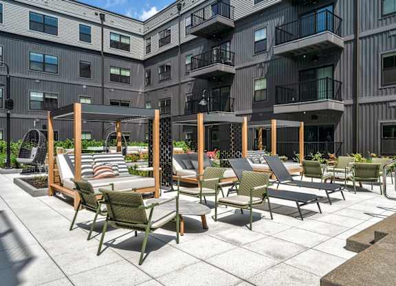 A patio with chairs and tables is in front of a building.