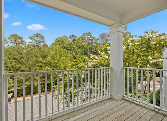 A white porch with a white railing and a view of trees.