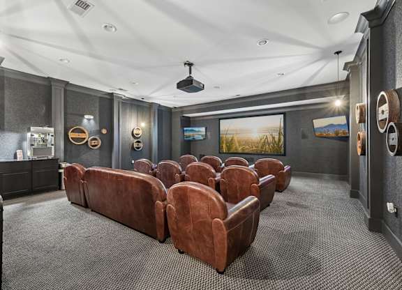 A home theater with a row of brown leather chairs.