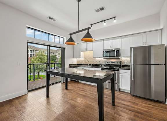 A modern kitchen with a black table and stainless steel appliances.