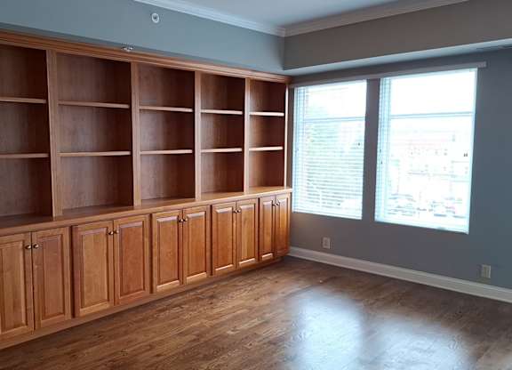 an empty living room with wooden cabinets and a window